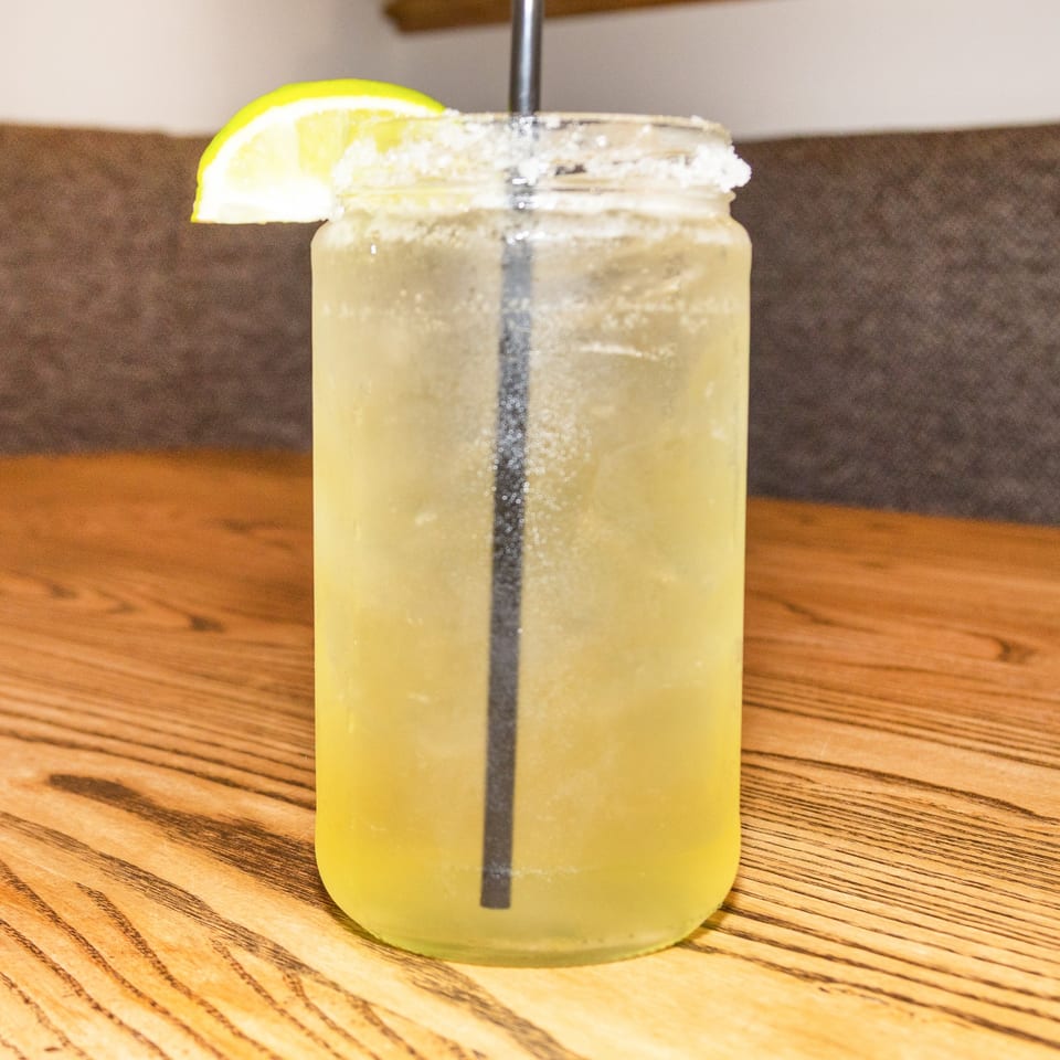 A Houligan's Corner margarita in a mason jar with a salted rim and lime wedge.